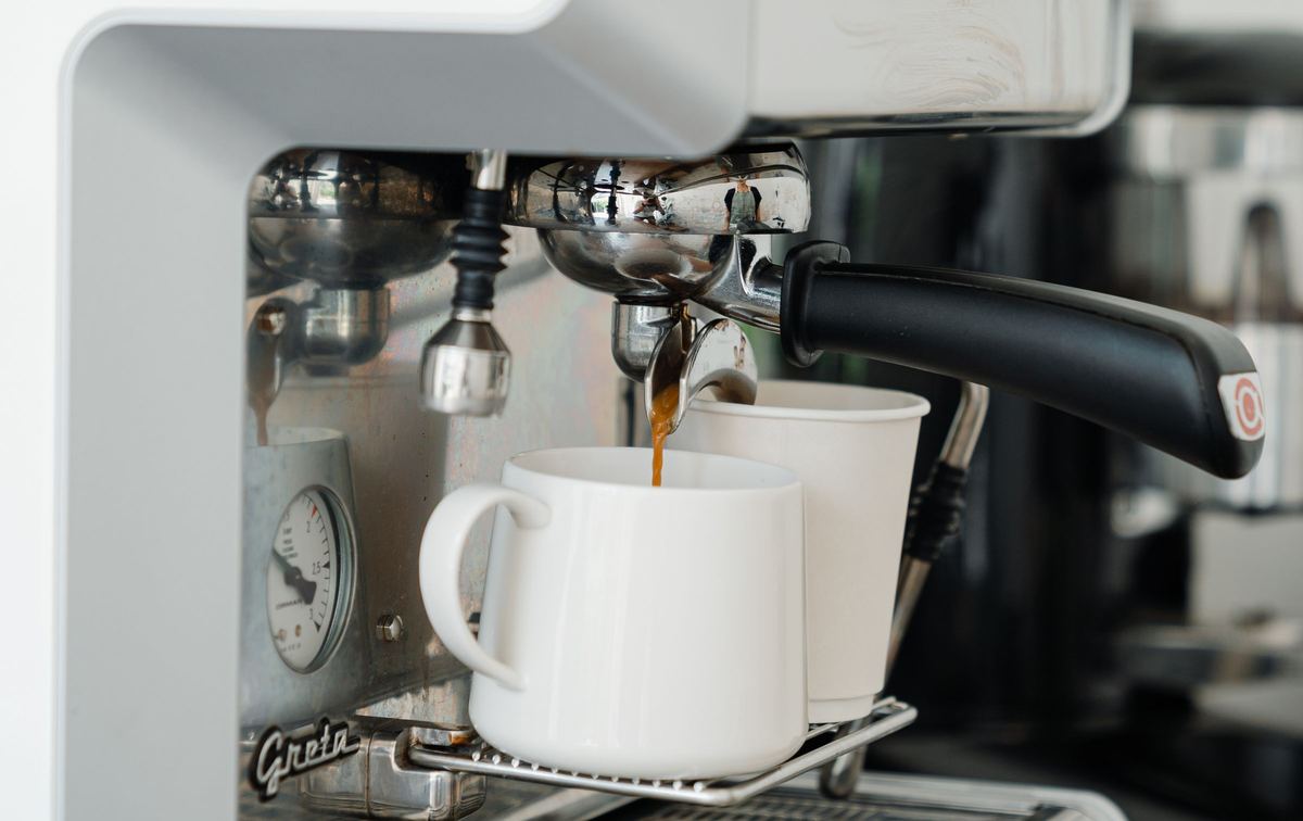Espresso machine pouring coffee into a white cup