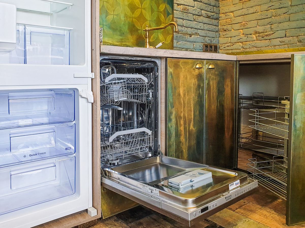 Built-in dishwasher open beside an integrated freezer