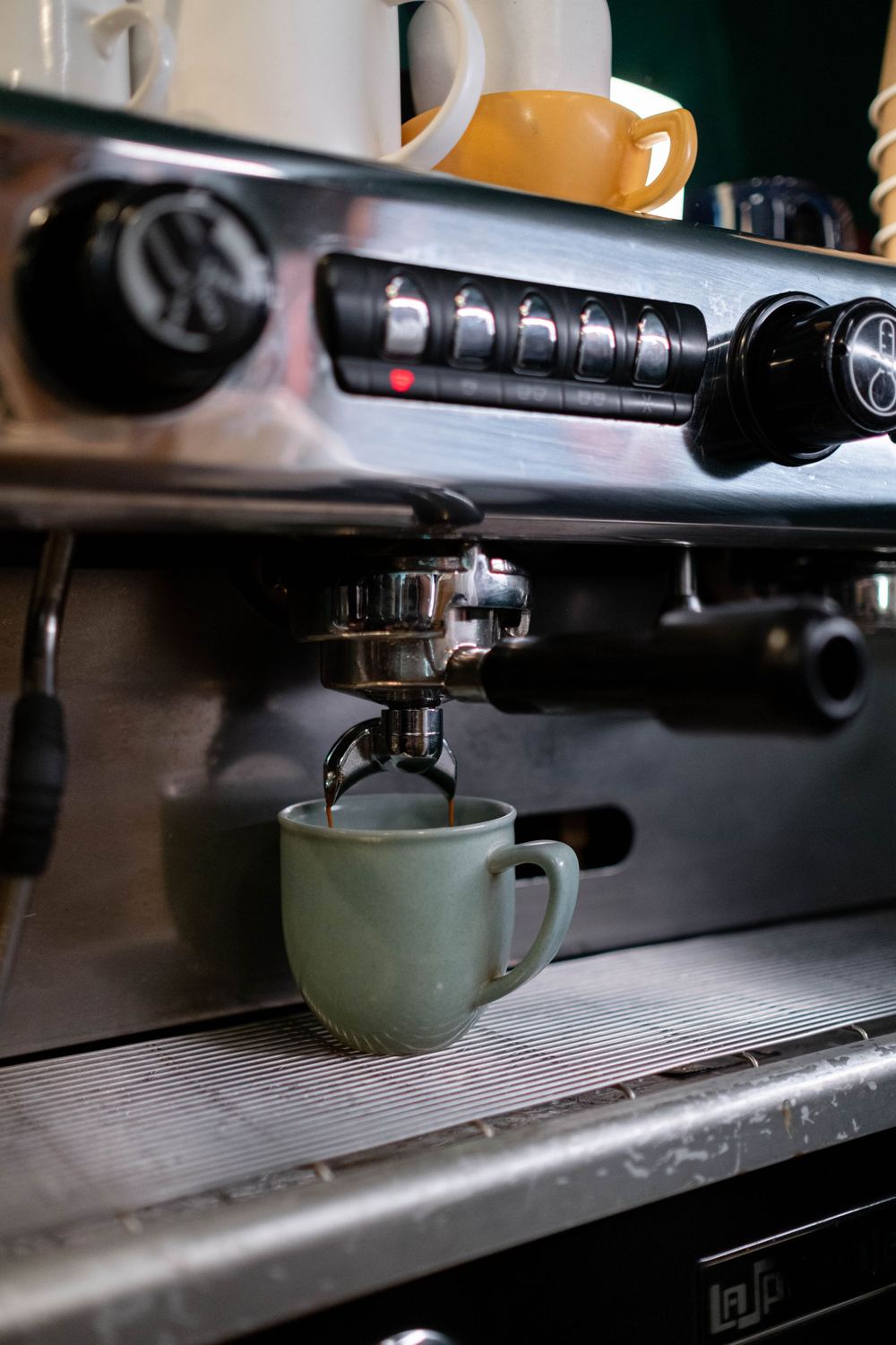 Espresso machine brewing into a green cup