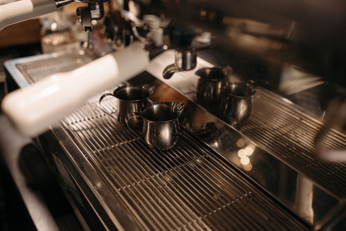 Close-up of an espresso machine drip tray with milk jugs